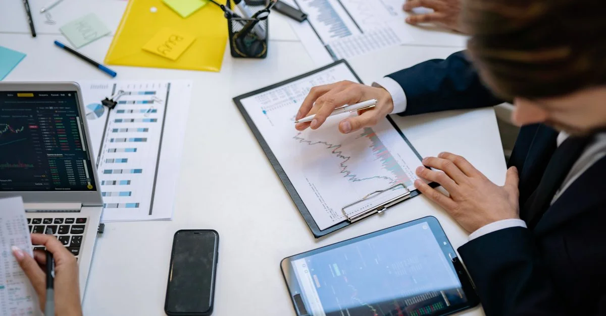 Équipe examinant des graphiques financiers et des données numériques sur des tablettes dans un environnement de bureau.