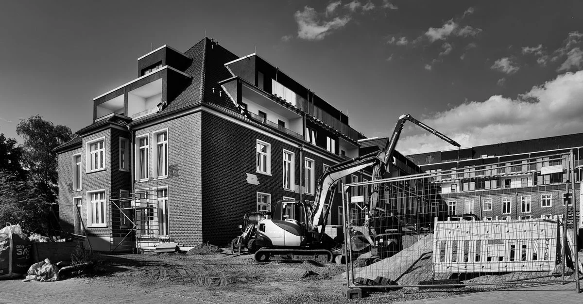 Image monochrome d'un chantier présentant un immeuble moderne en brique en cours de développement.
