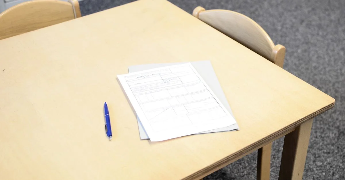 Bureau de classe vide avec documents et stylo, idéal pour des thèmes éducatifs.