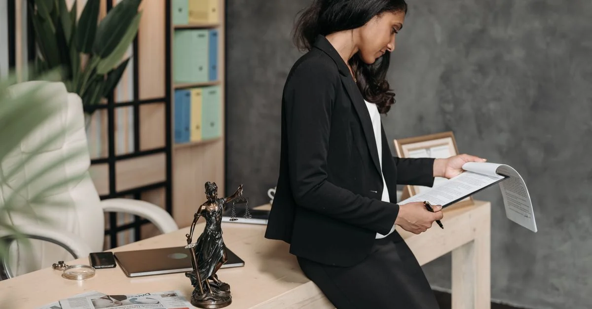 Une femme professionnelle en costume d'affaires examine des documents juridiques à son bureau.