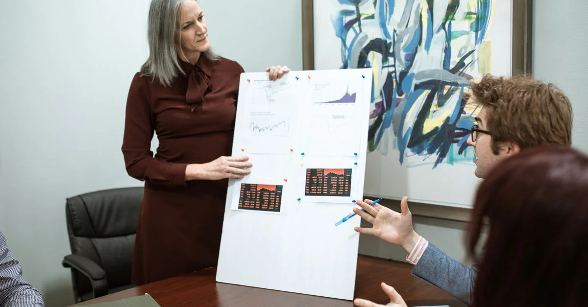 Des professionnels discutent de graphiques lors d'une présentation de réunion dans une salle de conférence moderne.