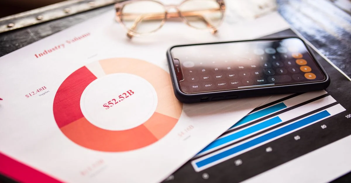Smartphone sur des documents d'affaires avec graphiques et courbes, illustrant une analyse financière.