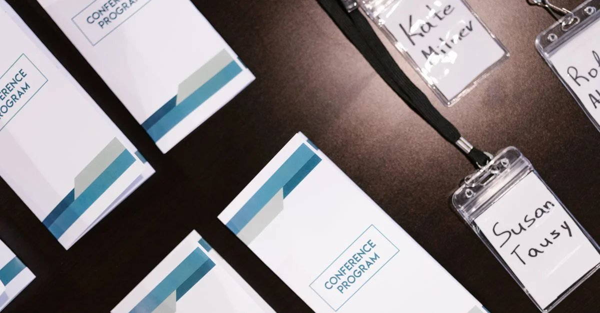 Vue en plongée des programmes de conférence et des badges nominatifs sur une table, idéal pour les visuels d'événements d'entreprise.