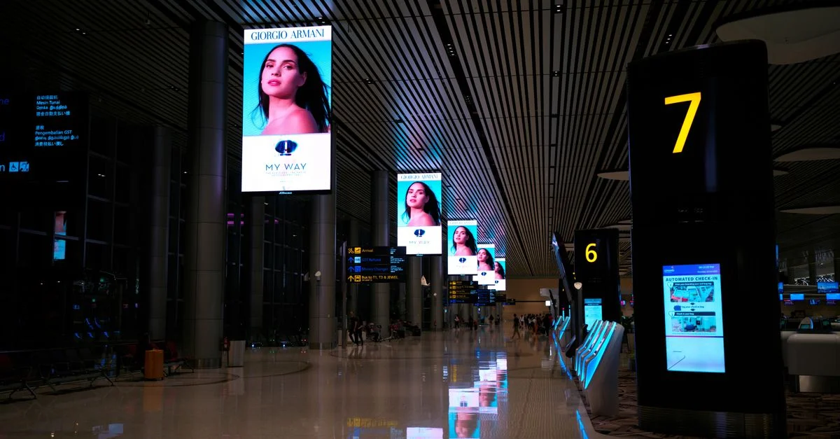 Couloir d'aéroport vide avec des écrans numériques et des sols brillants la nuit.