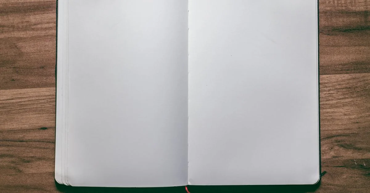 Une vue d'ensemble d'un carnet ouvert et vide sur un bureau en bois, parfait pour des projets de design ou d'écriture.