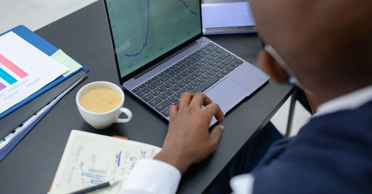 Un adulte professionnel examinant des graphiques financiers sur un ordinateur portable dans un bureau moderne.