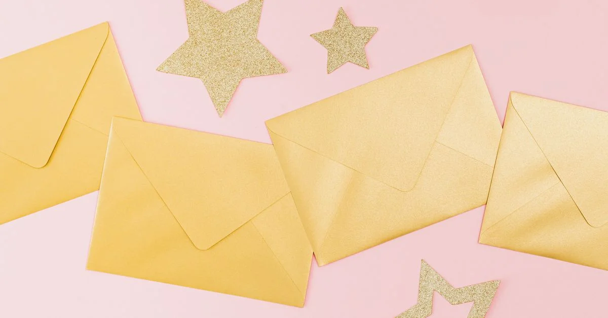 Enveloppes dorées et étoiles scintillantes sur un fond rose, parfaites pour les célébrations festives.