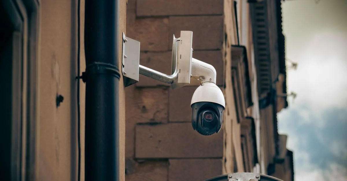 Caméra de vidéosurveillance fixée à un mur de bâtiment dans un environnement urbain, améliorant la sécurité.