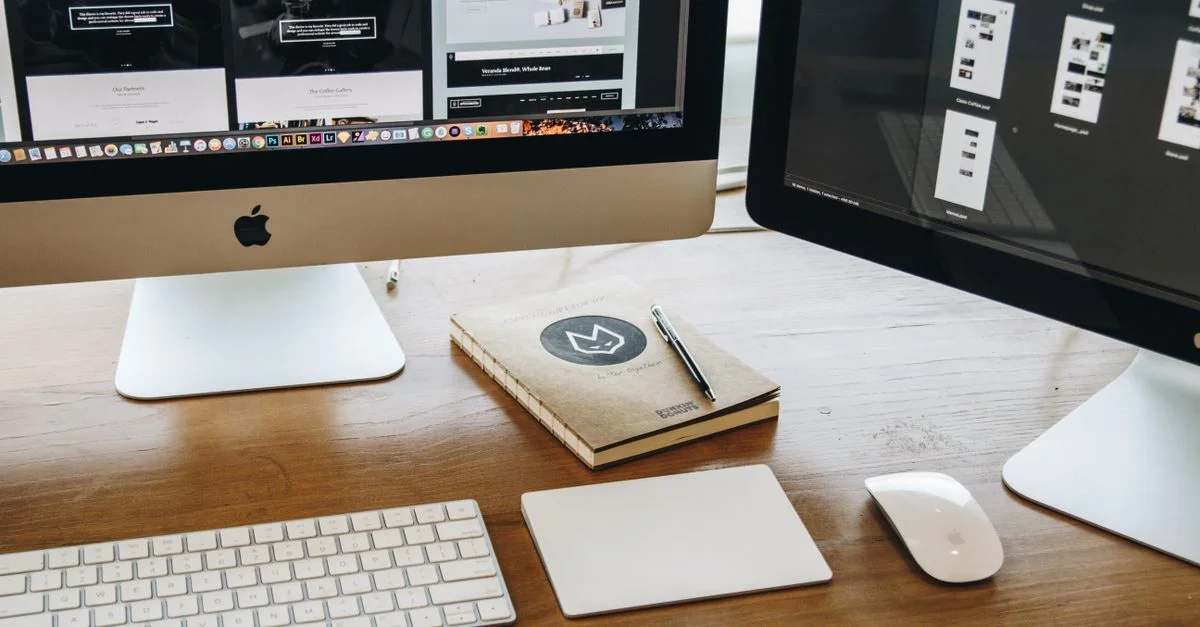 Un bureau minimaliste avec deux écrans, un clavier, une souris et un carnet pour la productivité.