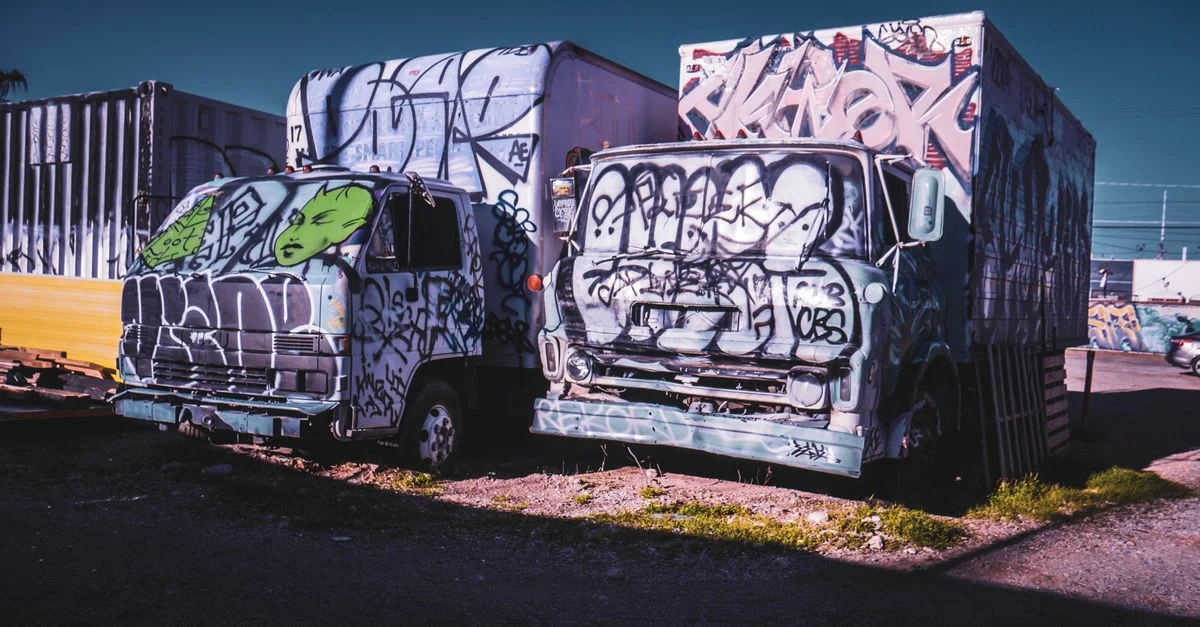 Camions abandonnés recouverts de graffitis colorés, mettant en avant la décadence urbaine et l'art de rue.