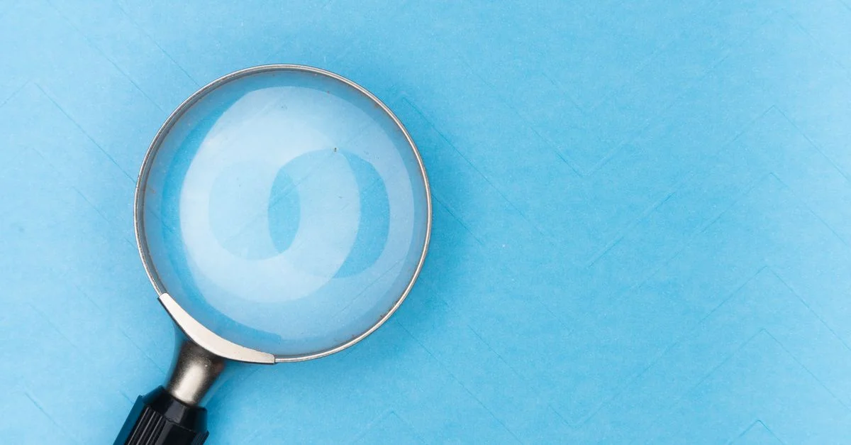 Gros plan d'une loupe sur une surface bleue, idéal pour les thèmes de recherche et d'exploration.