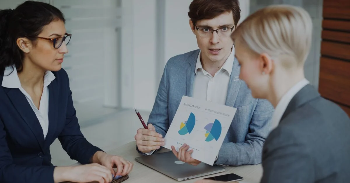 Équipe de professionnels discutant des stratégies de vente avec des graphiques dans un bureau moderne.