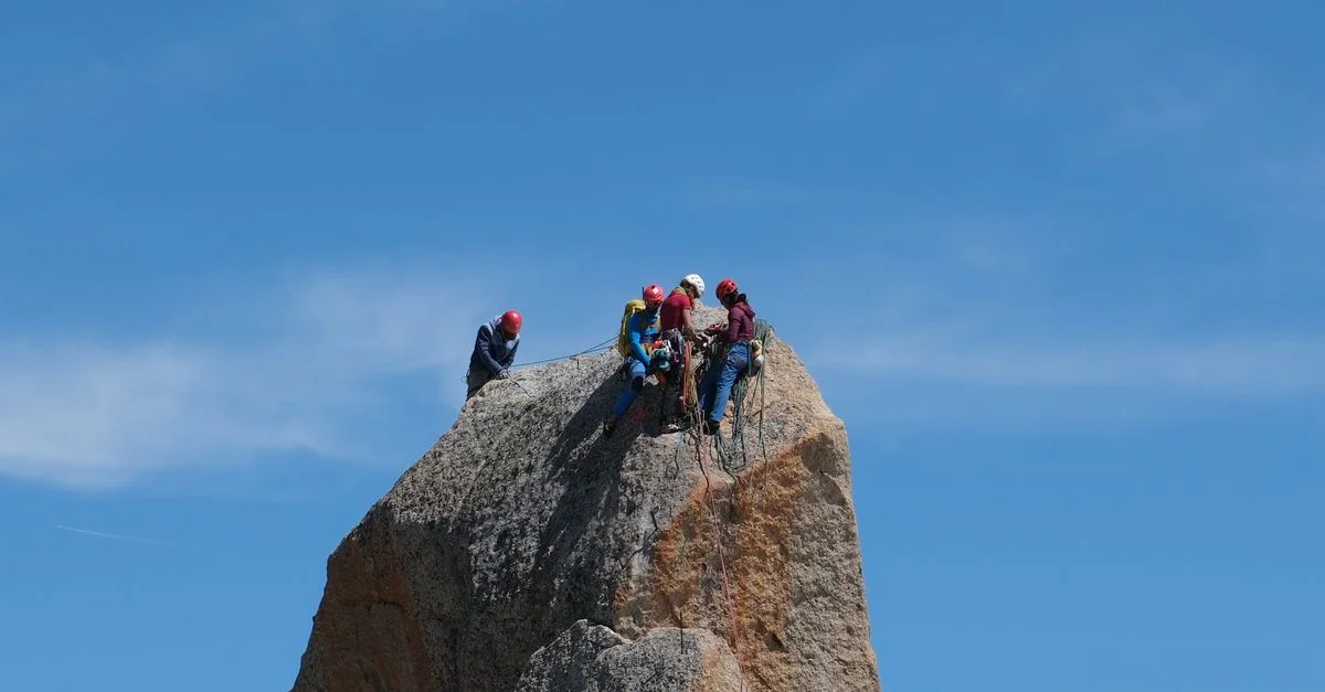 Groupe de grimpeurs atteignant un sommet par une journée claire, illustrant le travail d'équipe et l'aventure.