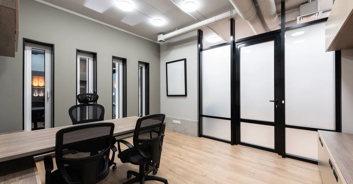 Bureau spacieux avec design moderne, parquet en bois et cloisons en verre.