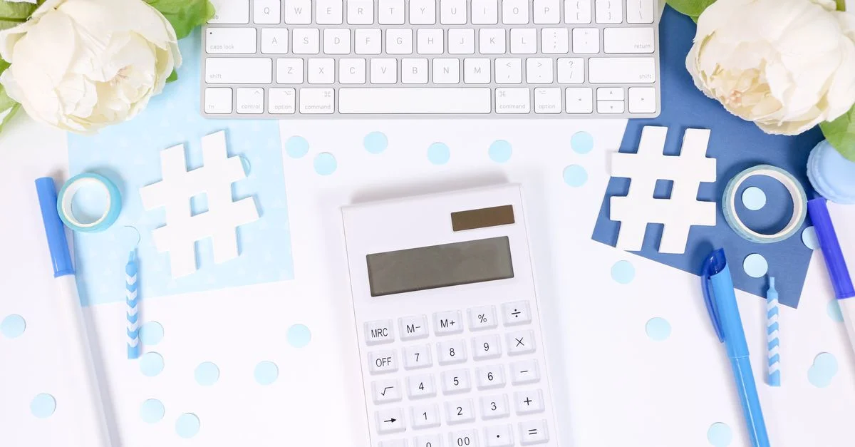 Photo de style avec une calculatrice, des fleurs blanches et des fournitures de bureau bleues sur un bureau.
