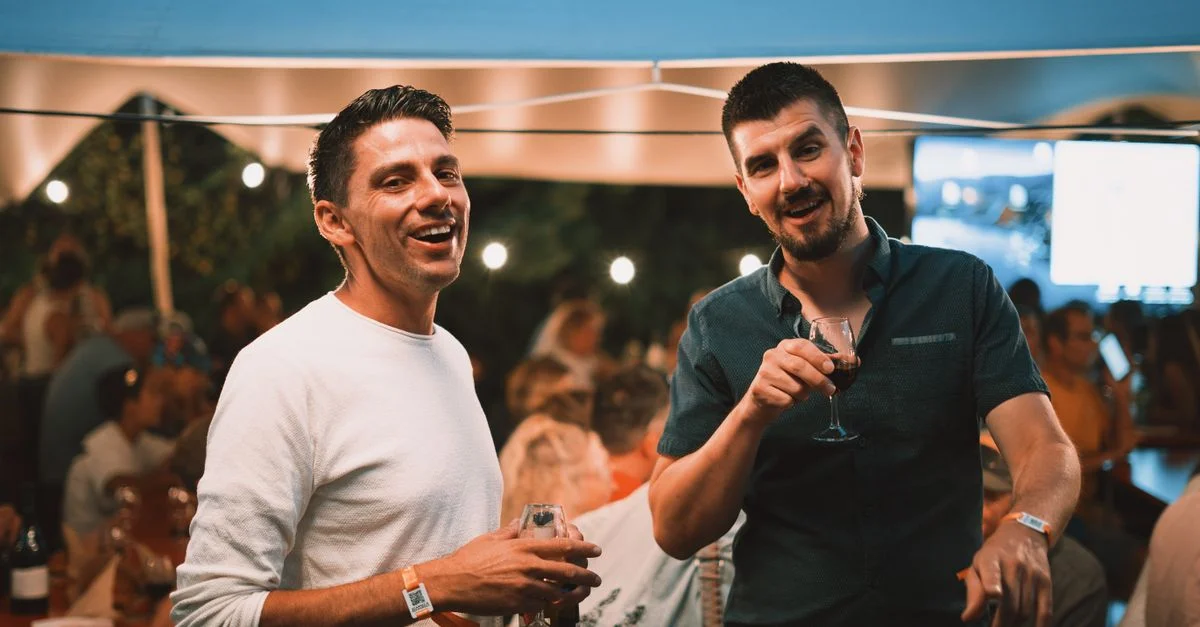 Deux amis profitent d'une soirée conviviale autour d'un verre, capturant l'ambiance festive et animée.