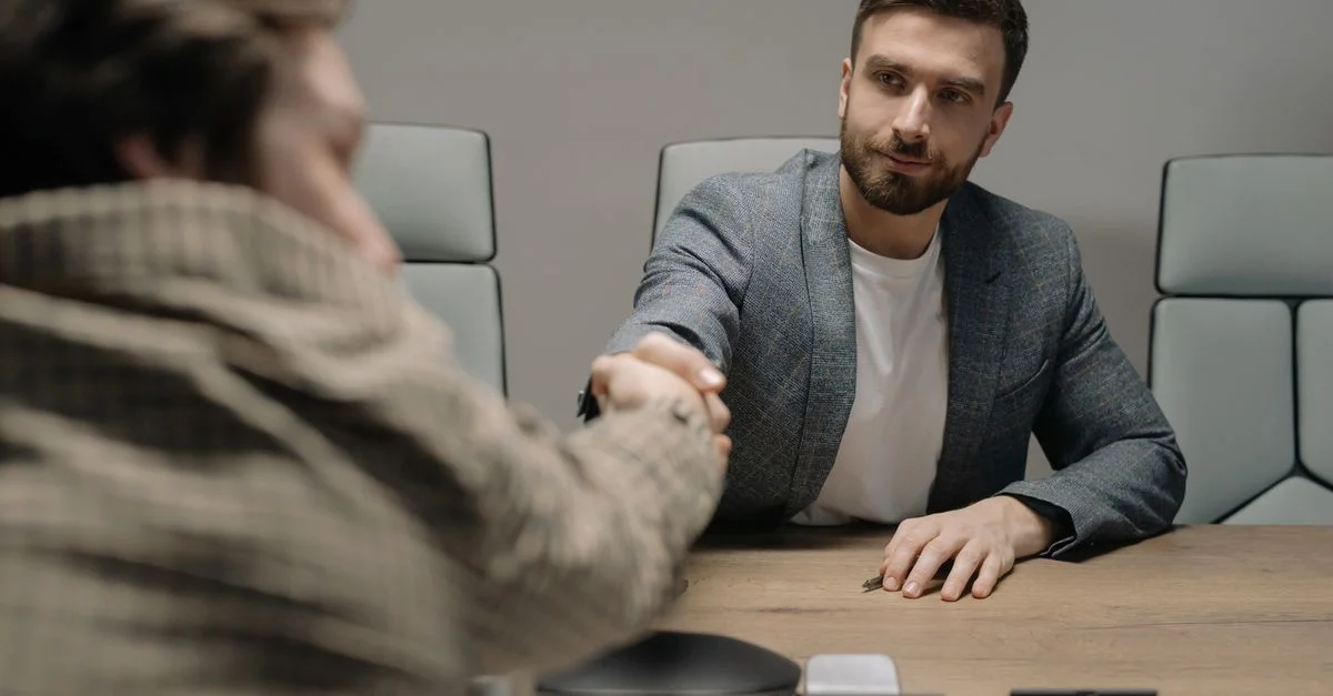Deux hommes d'affaires se serrant la main au-dessus d'un bureau en bois dans un cadre de bureau moderne.