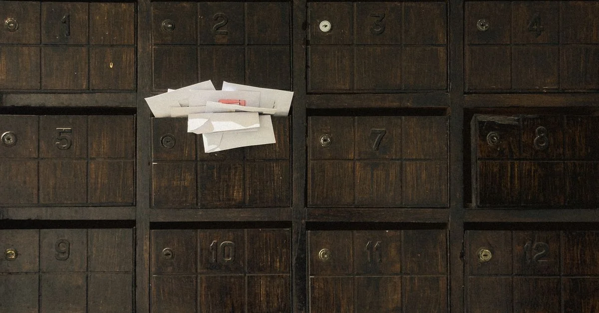 Ancienne boîte aux lettres en bois montrant des fentes numérotées et des lettres insérées.