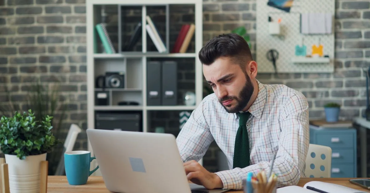 Un professionnel masculin concentré travaillant sur un ordinateur portable dans un bureau moderne et élégant.
