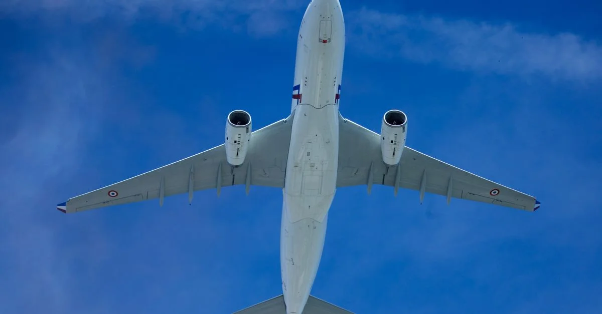 Vue en contre-plongée d'un avion de ligne volant haut contre un ciel bleu dégagé.