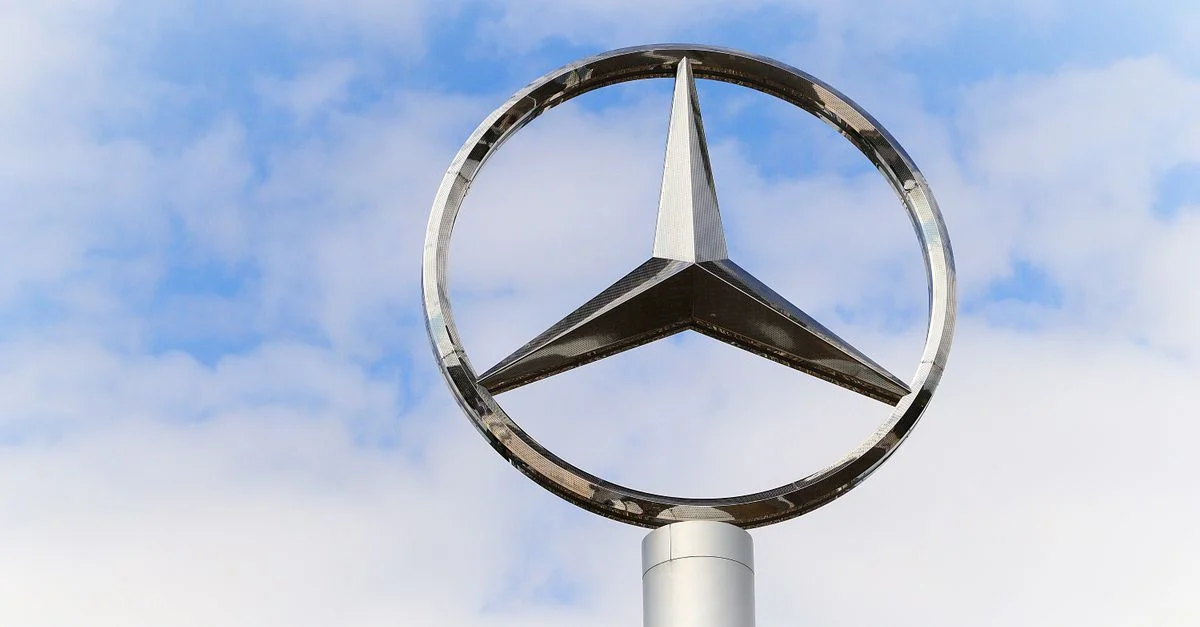 Logo Mercedes-Benz en acier inoxydable sur fond de ciel bleu nuageux.