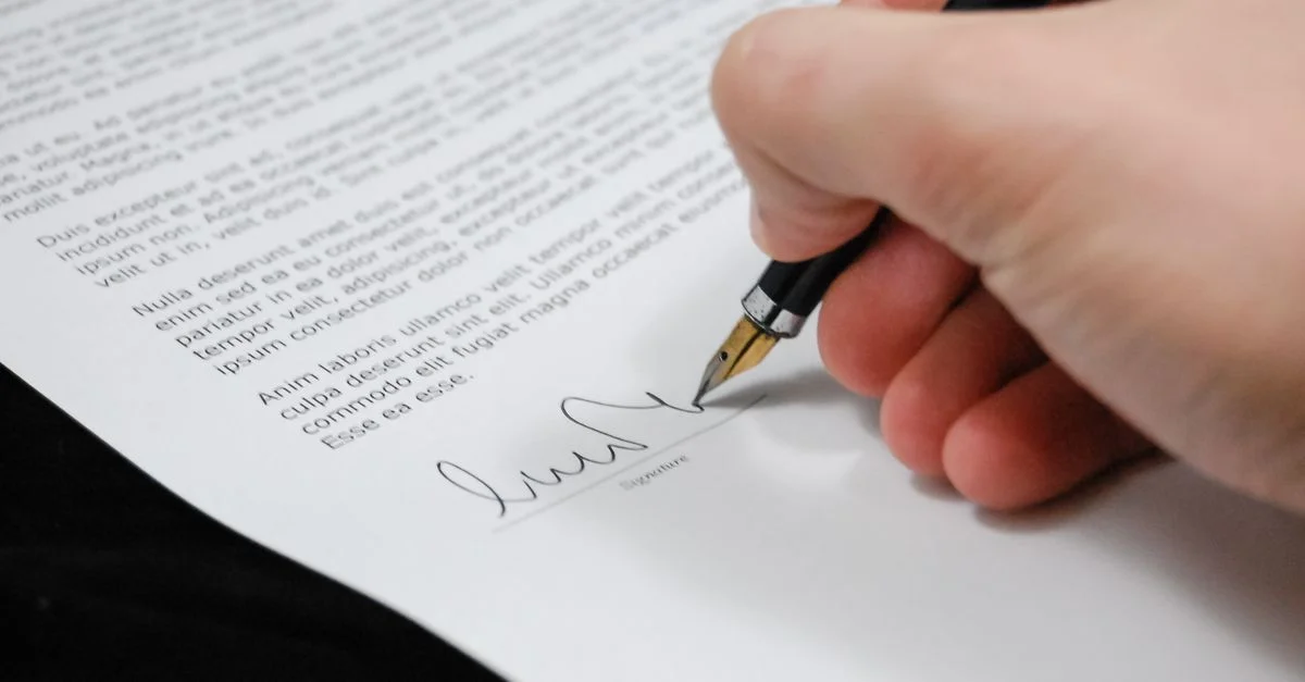 Gros plan d'une main signant un document légal avec un stylo plume, symbolisant la signature et l'accord.