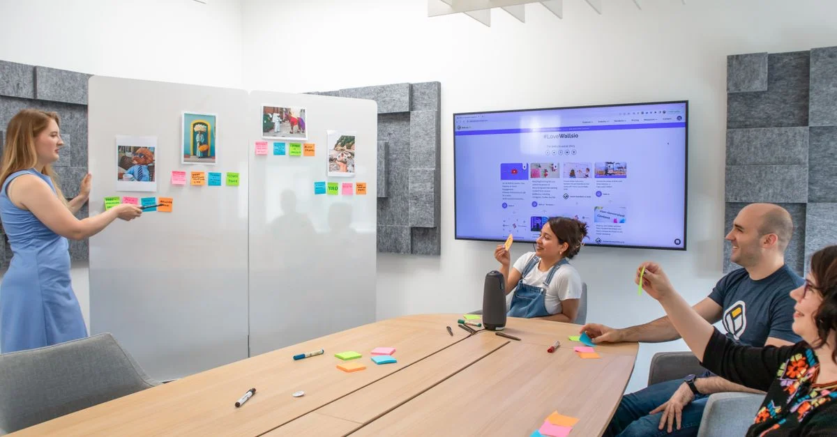 Un groupe de personnes dans un cadre de bureau collaborant avec des post-it sur un tableau blanc.