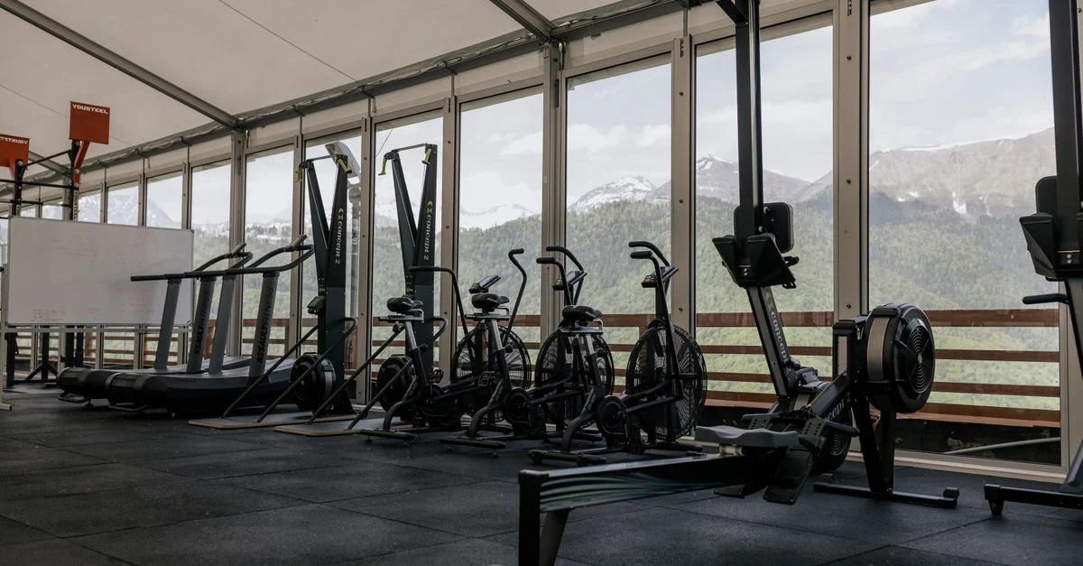 Salle de gym intérieure spacieuse avec des équipements à la pointe de la technologie et des vues pittoresques sur les montagnes à travers de grandes fenêtres.