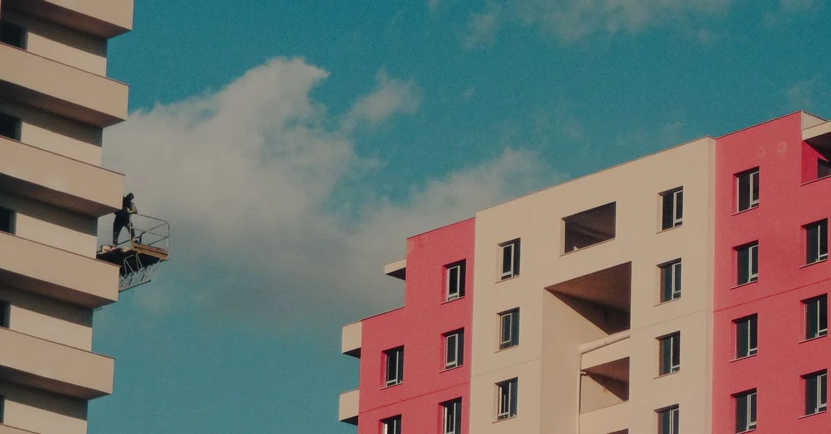 Immeubles colorés avec un travailleur sur une plate-forme suspendue contre un ciel dégagé.