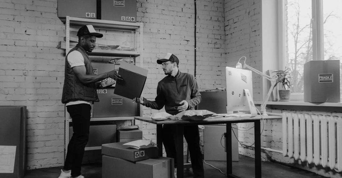 Collègues d'affaires travaillant avec des colis, mettant en avant la logistique et le travail d'équipe dans un bureau moderne.