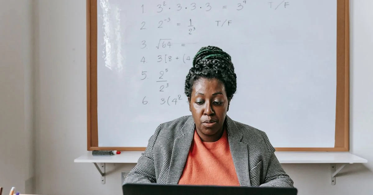 Une femme afro-américaine enseignant un cours de mathématiques en ligne depuis chez elle en utilisant un laptop.