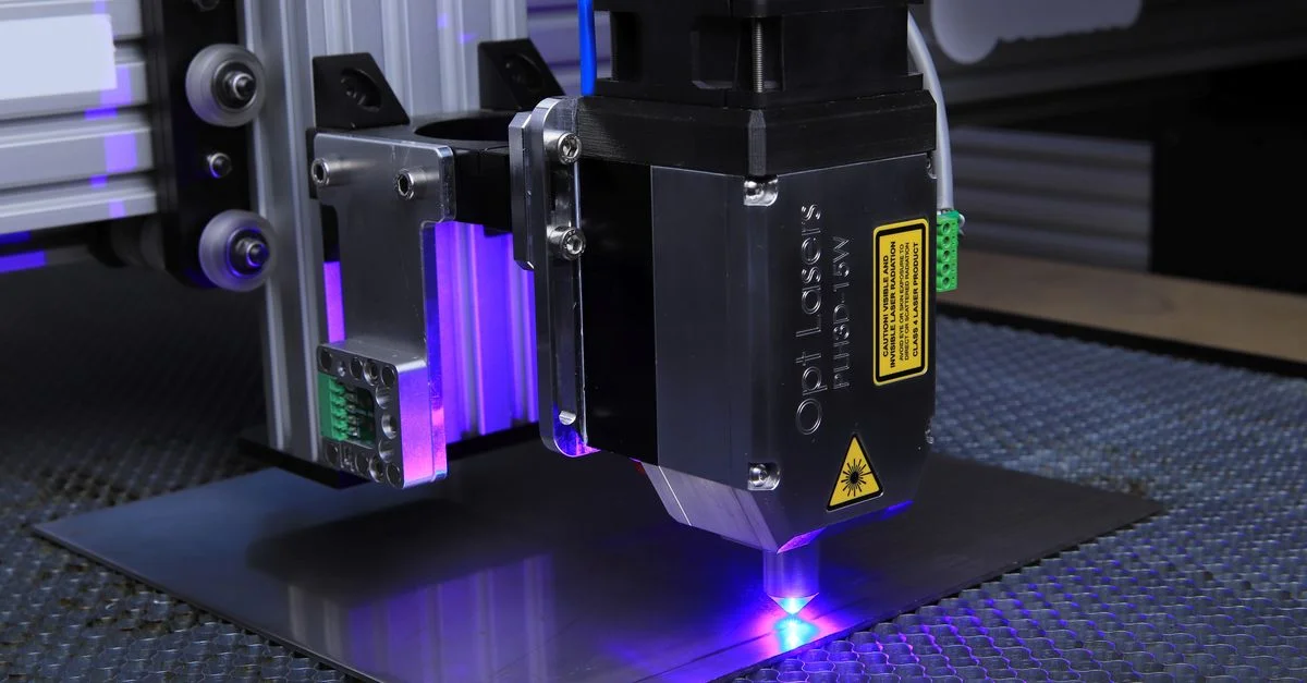 Gros plan d'une machine de gravure au laser fonctionnant sur une surface métallique avec une lumière laser bleue.