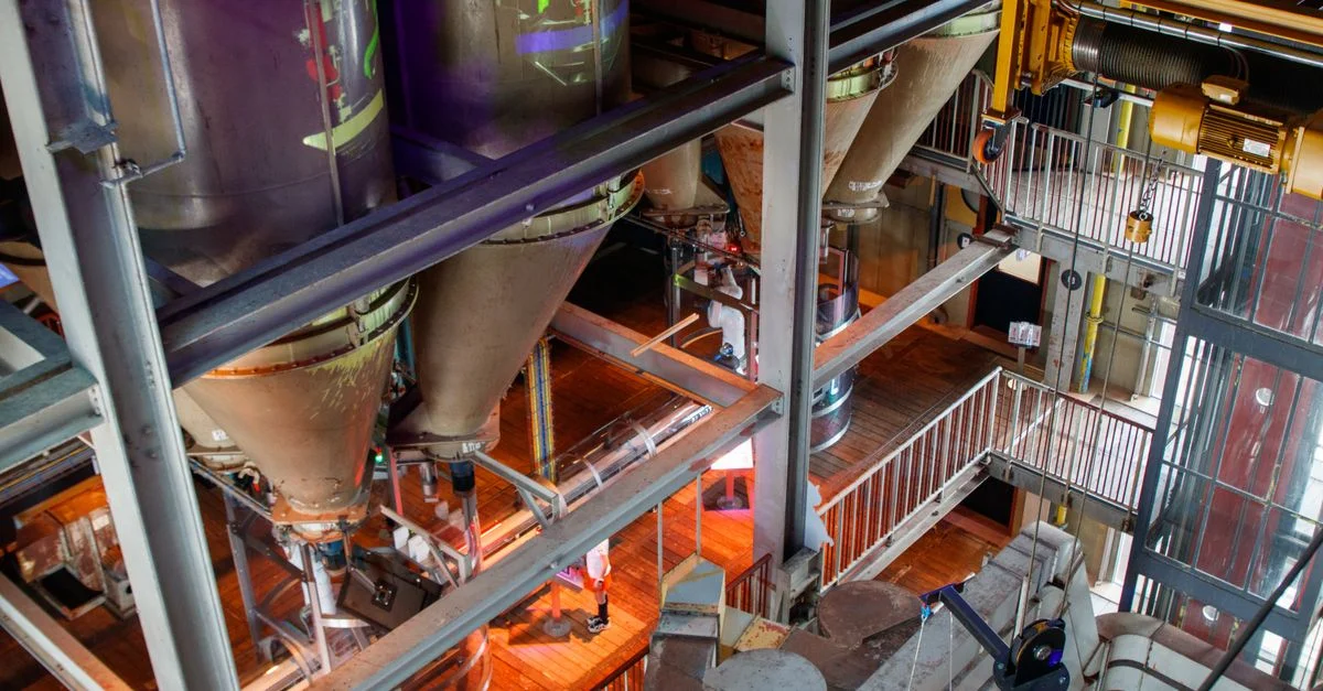 Vue plongée des silos industriels à l'intérieur d'une usine, présentant des machines complexes.