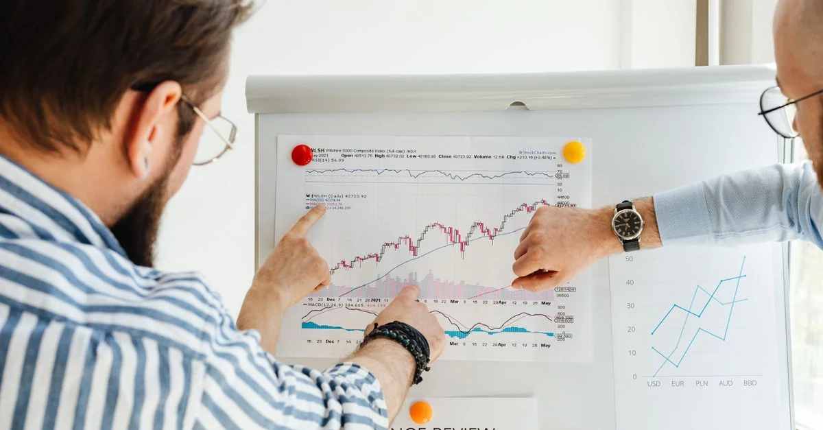 Collègues discutant des tendances de données sur un tableau blanc avec des graphiques et des diagrammes.