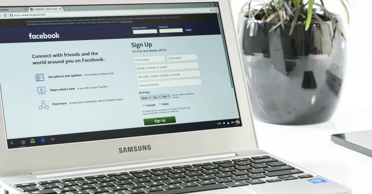 Ordinateur portable Samsung ouvert affichant la page d'inscription Facebook à côté d'une plante en pot. Idéal pour des thèmes technologiques.