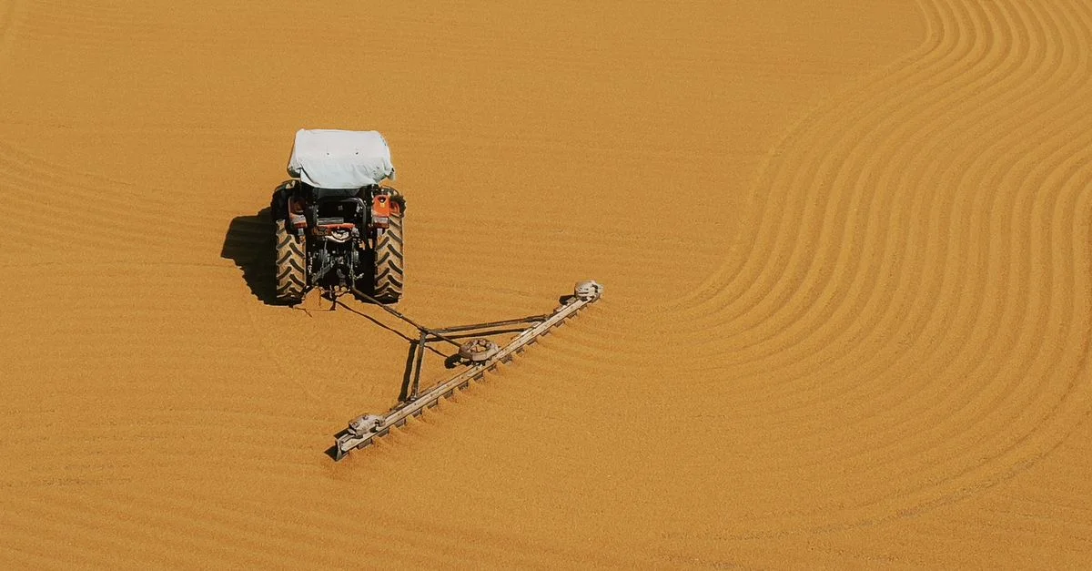 Vue aérienne d'un tracteur créant des lignes précises sur un champ cultivé.