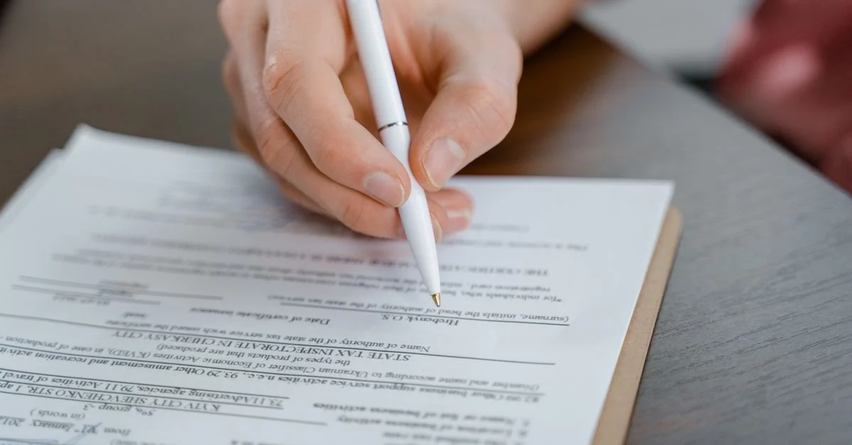 Une main tenant un stylo en train de signer un document, gros plan avec un accent sur le papier.