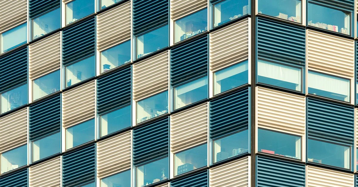 Gros plan de la façade d'un bâtiment de bureau moderne avec des motifs géométriques répétitifs et des fenêtres.
