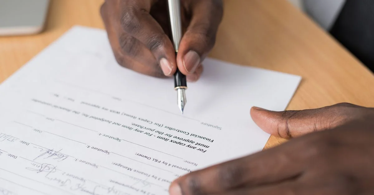 Gros plan des mains d'un homme signant un document officiel à l'intérieur.