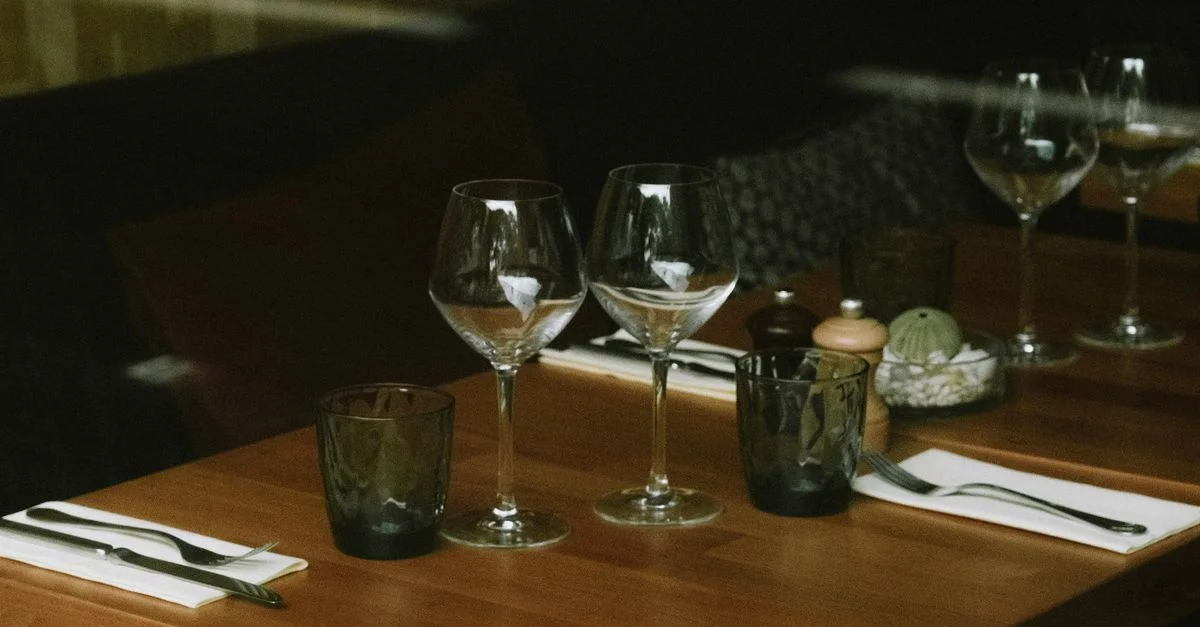 Une table de restaurant élégante, dressée avec des verres à vin et des couverts, parfaite pour une ambiance de dîner.