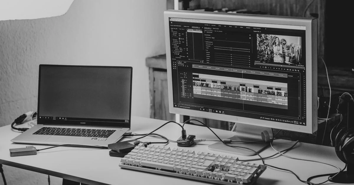 Un espace de travail monochrome avec un ordinateur portable et un moniteur pour le montage vidéo.