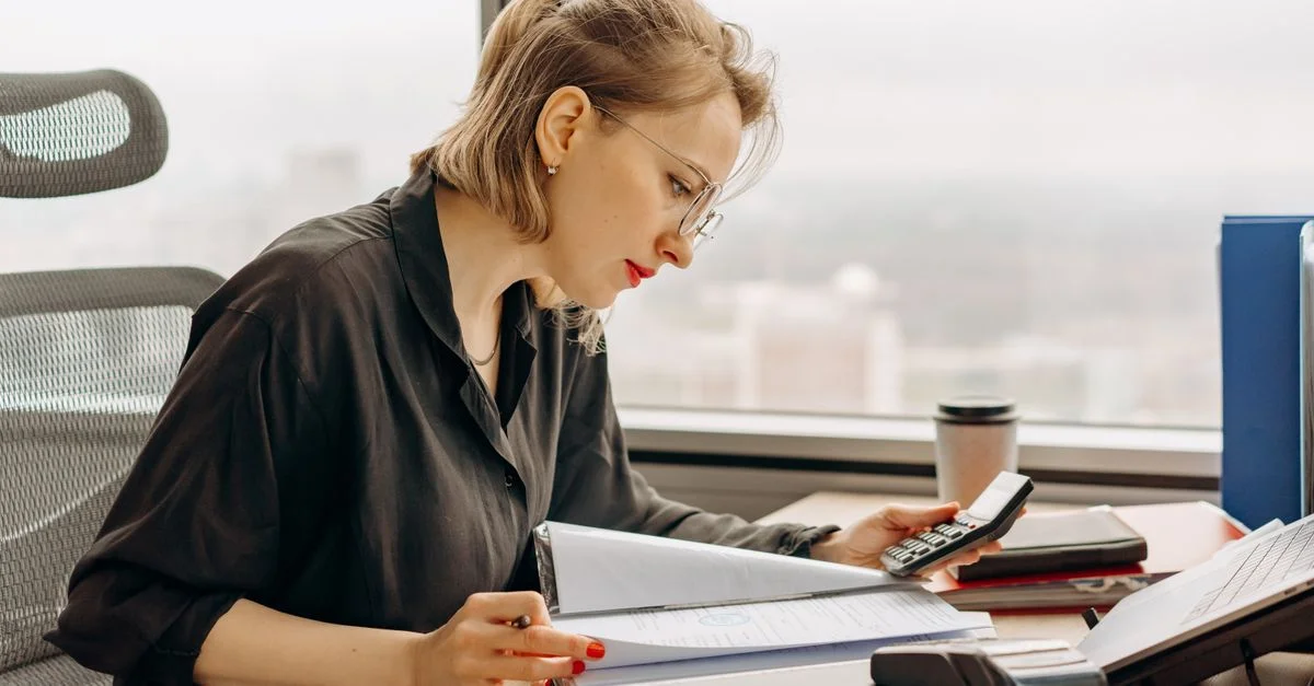 Femme comptable calculant des documents financiers au bureau.