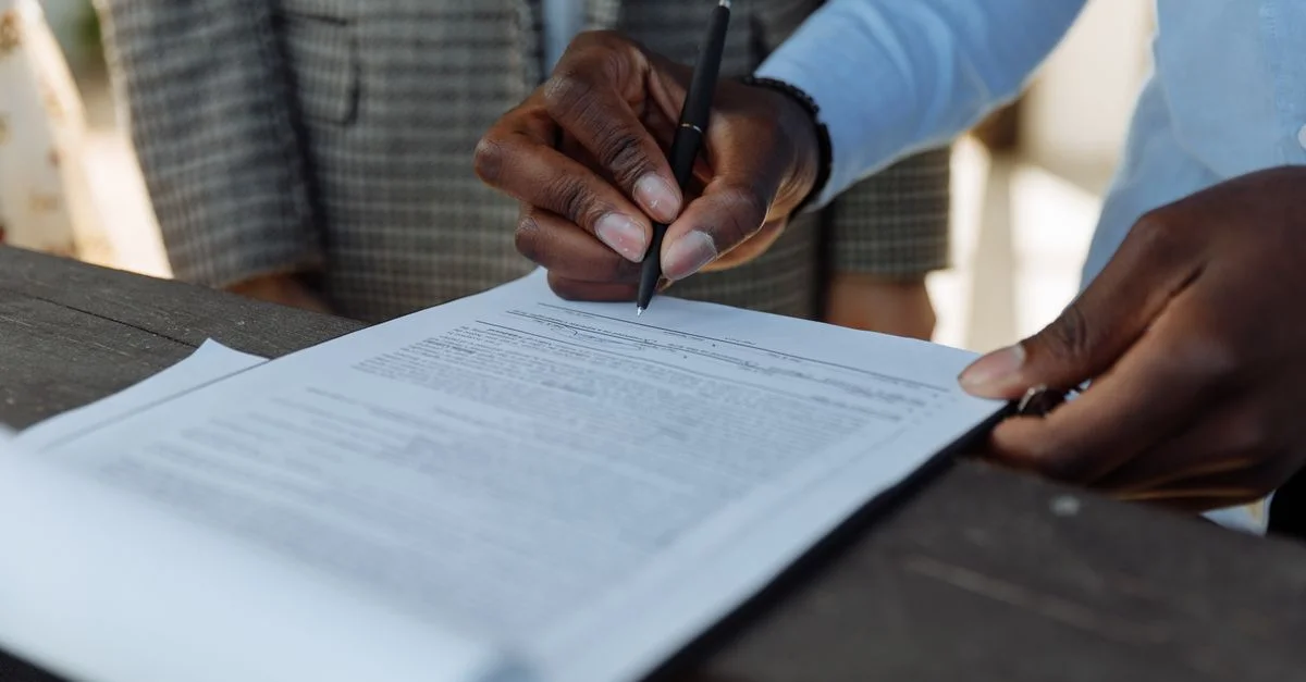 Gros plan de professionnels du secteur signant un document avec un stylo à l'intérieur.