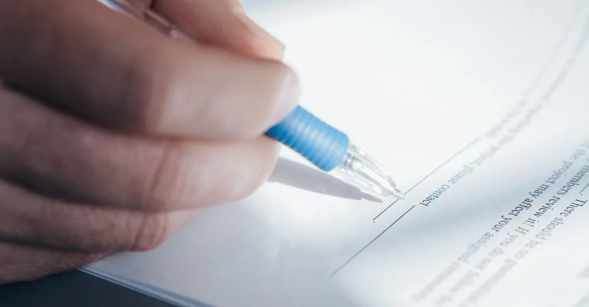 Une image en gros plan montrant une main tenant un stylo tout en signant un document.