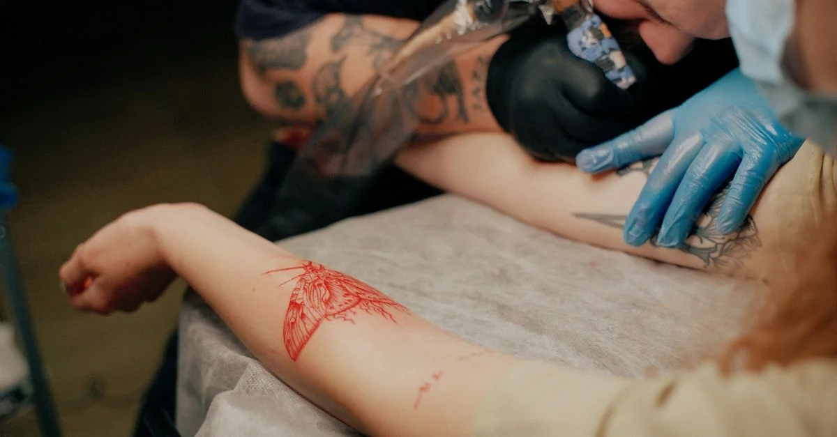 Vue détaillée d'un tatoueur tatouant le bras d'un client dans un studio.