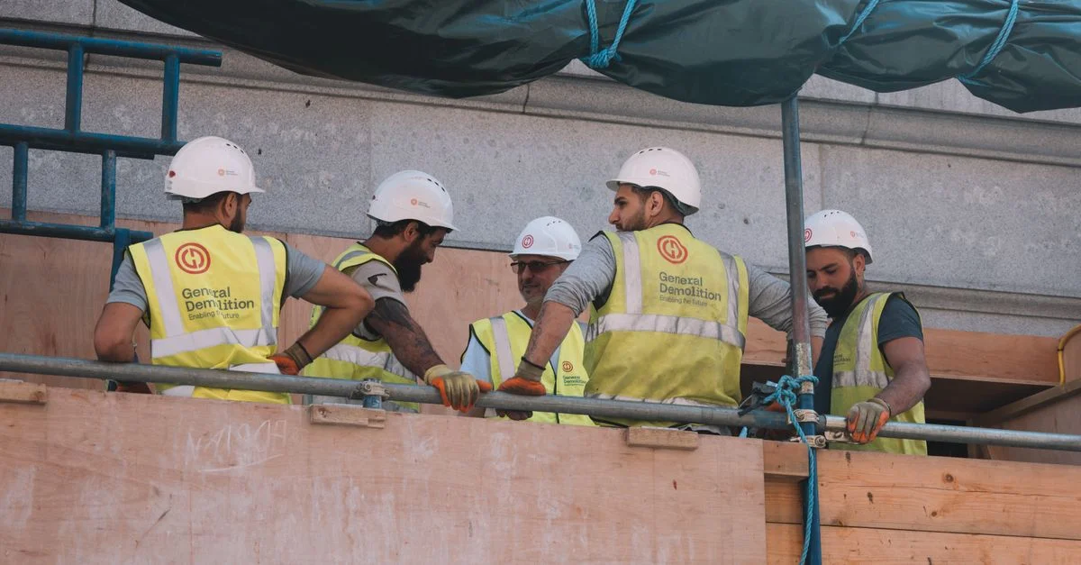 Groupe de travailleurs de la construction en équipement de sécurité collaborant sur un site de construction en ville.