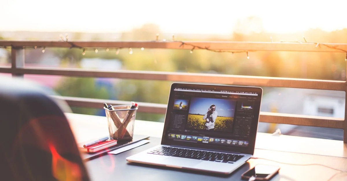 Un espace de travail moderne sur un balcon avec un ordinateur portable et un smartphone au coucher du soleil, capturant un environnement de travail créatif.