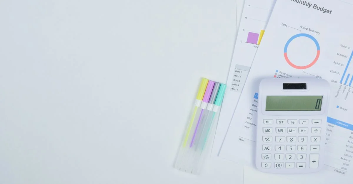 Bureau minimaliste avec une calculatrice, des documents de planification budgétaire et des stylos colorés.