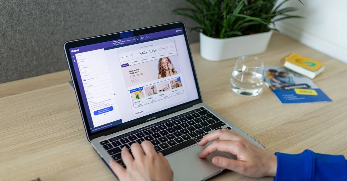 Une personne naviguant dans un magasin en ligne sur un ordinateur portable, à un bureau moderne à l'intérieur.