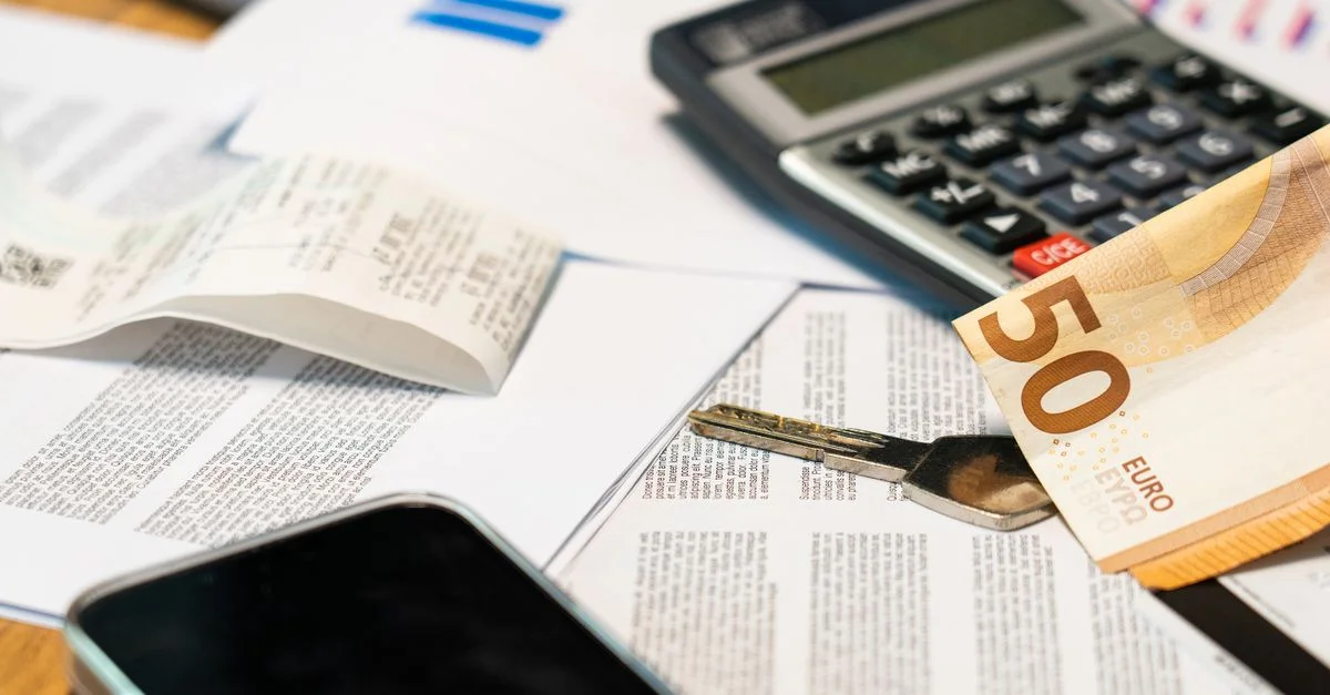 Vue de dessus de documents financiers, billet en euros, calculatrice, smartphone et clé pour la gestion du budget.